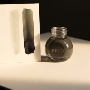 Oak Gall Brown, 30 ml — A small round glass bottle of dusty green-brown ink beside a sheet showing a brush wash grading from pale to dark.