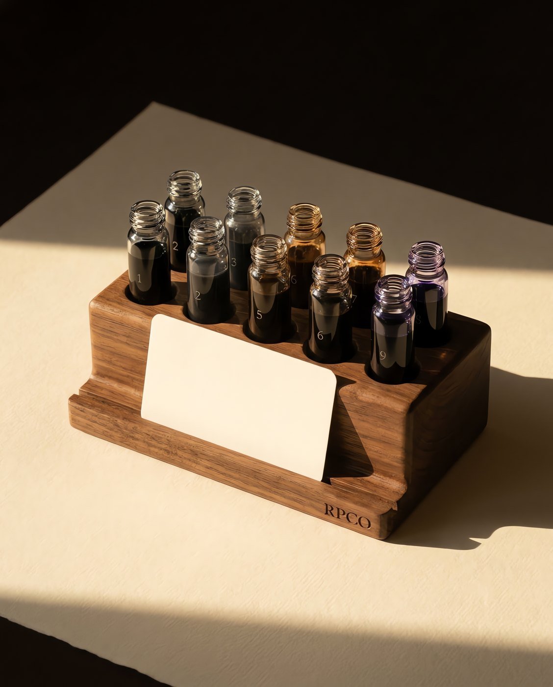 Nine-Swatch Sample Rack — A turned walnut rack holding nine small numbered vials of different coloured inks with a blank swatch card in a front slot.