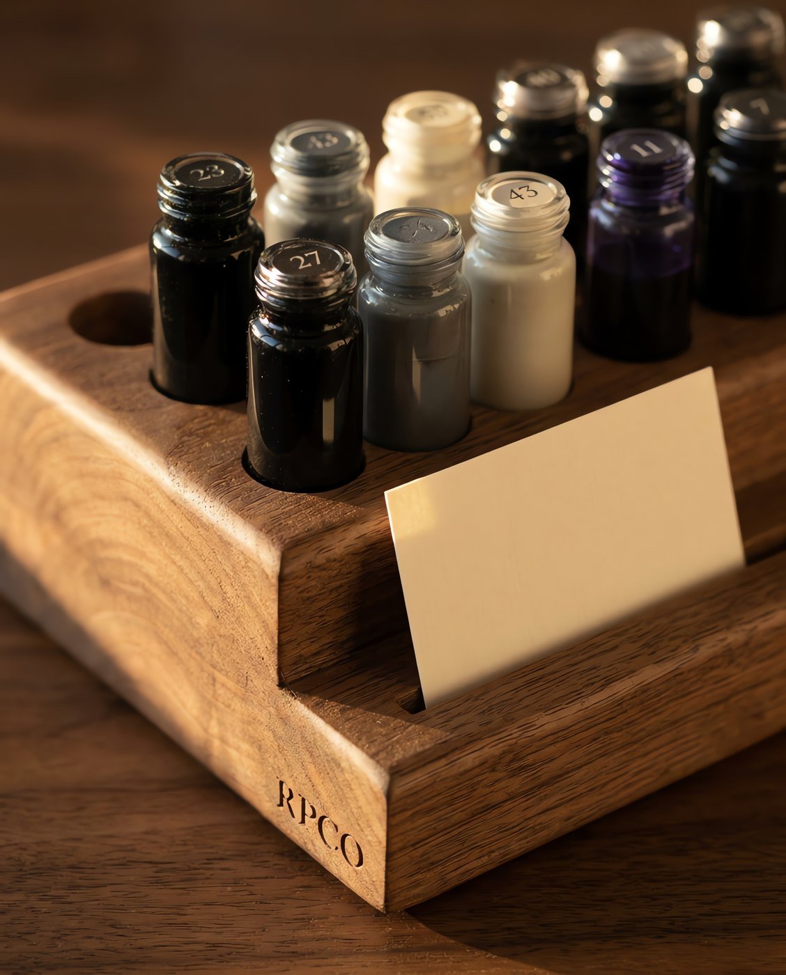 Nine-Swatch Sample Rack — A turned walnut rack holding nine small numbered vials of different coloured inks with a blank swatch card in a front slot in close detail.