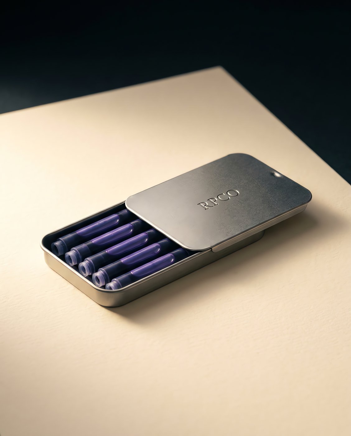 Cartridge Box, Registry Violet — A small slide-top metal tin lying open with twelve violet ink cartridges arranged in two rows.