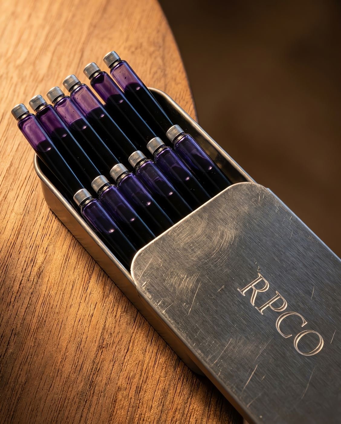 Cartridge Box, Registry Violet — A small slide-top metal tin lying open with twelve violet ink cartridges arranged in two rows in close detail.