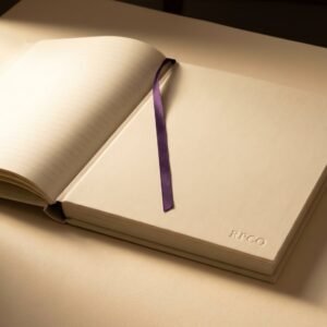 Laid Folio Notebook, A4 — A large A4 notebook in cream book cloth with a blind debossed mark, lying open and perfectly flat showing cream laid ruled pages and a ribbon.