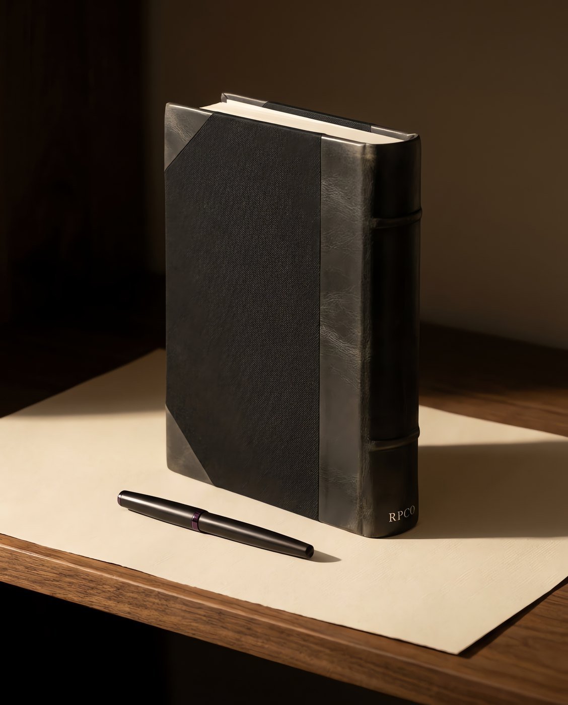 Ledger Book, Half-Bound — A thick half-bound ledger book with a rounded backed spine, cloth boards and leather-grain corners, standing on a shelf beside a closed pen.
