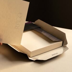 Laid Writing Ream, 90 gsm — An open ream wrapper with a thick stack of cream laid A4 paper, one sheet held up to the light showing a watermark.