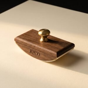 Walnut Rocker Blotter — A curved oiled walnut rocker blotter with a brass pin handle and a stained cream blotting sheet clipped underneath.