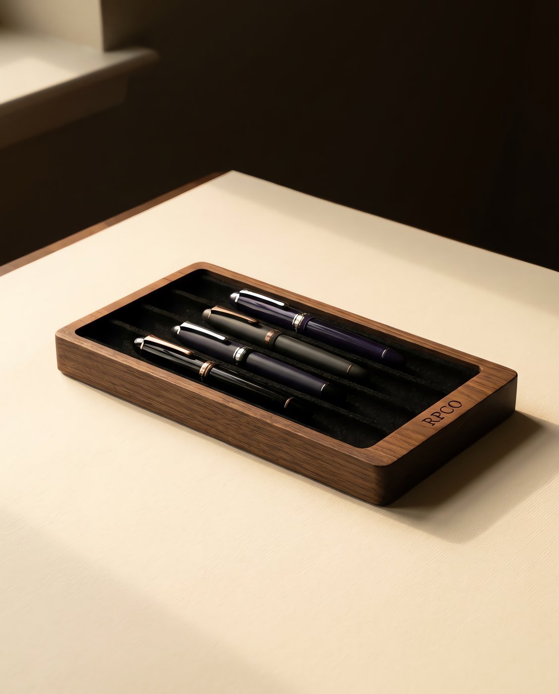 Pen Tray, Walnut — A shallow oiled walnut tray with four felt-lined channels holding four different fountain pens, thumb reliefs cut into the ends.