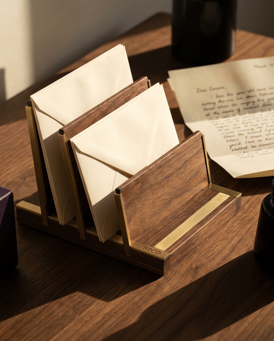 Letter Rack, Three Division — A walnut and brass three-division letter rack with rising dividers, holding cream envelopes at three different heights in use on a desk.
