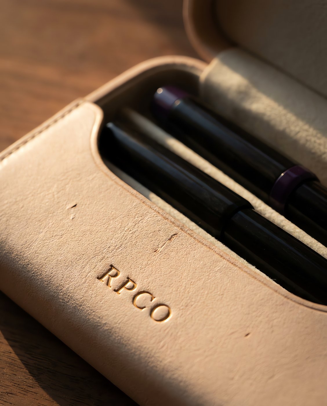 Pen Case, Two Pen — A hard-sided two pen case in pale undyed leather lying open to show two fountain pens separated by a felt-lined divider in close detail.