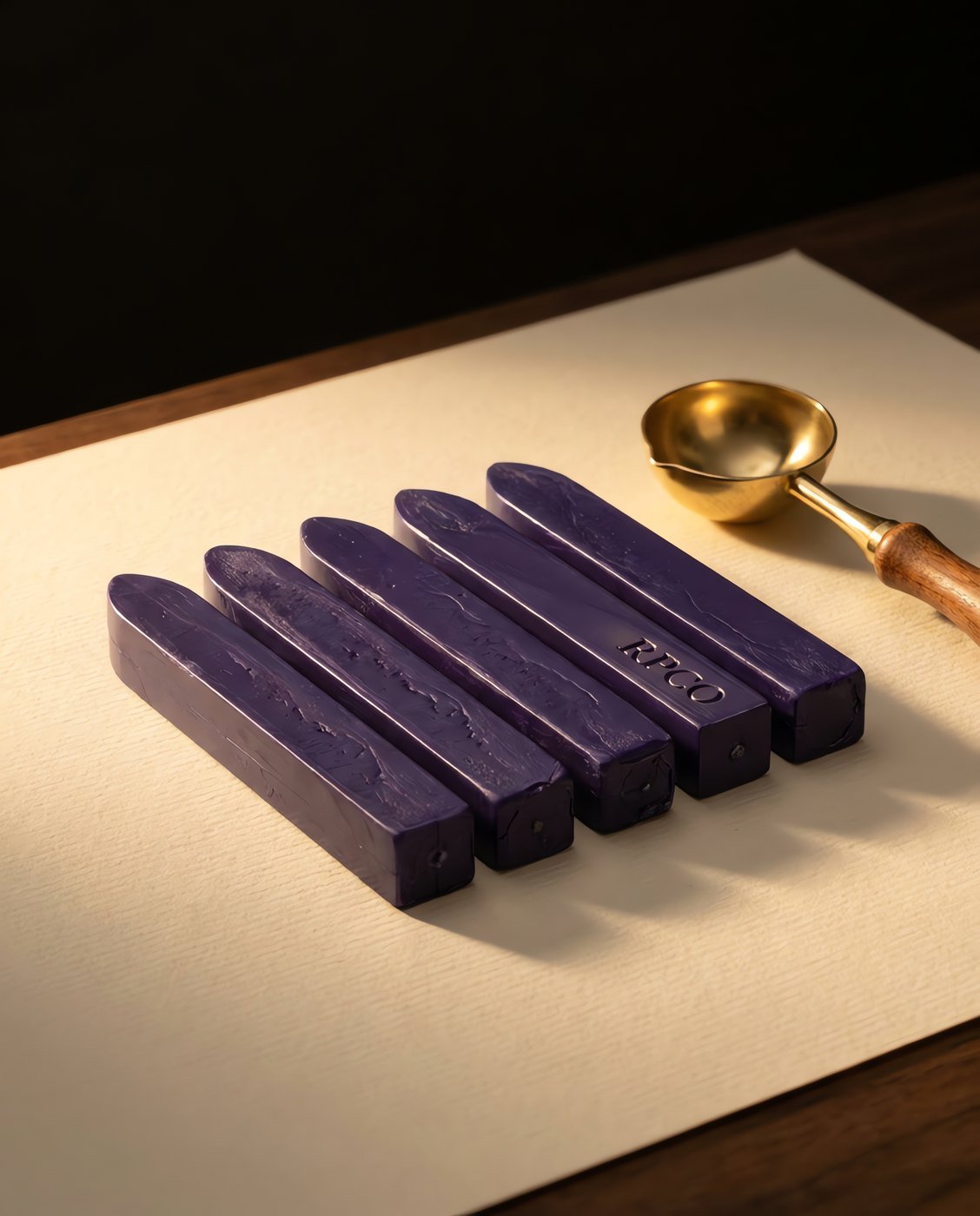 Sealing Wax Sticks, Registry Violet — Five sticks of deep violet sealing wax lying in a row on cream paper beside a brass melting spoon.
