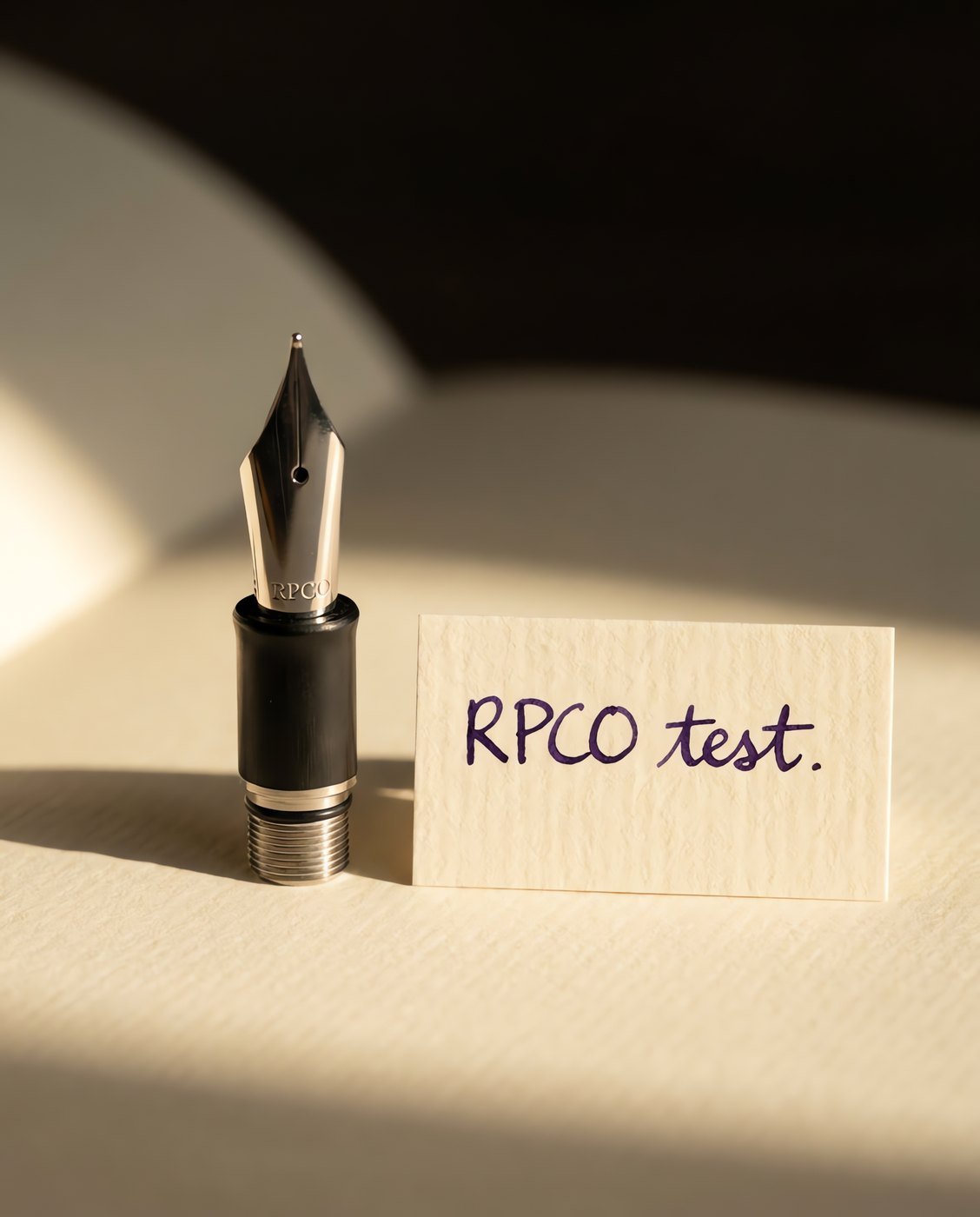 Nib Unit, No. 6 Steel — A complete screw-in fountain pen nib unit with a steel nib and a black ebonite feed, standing upright beside a small written test card.
