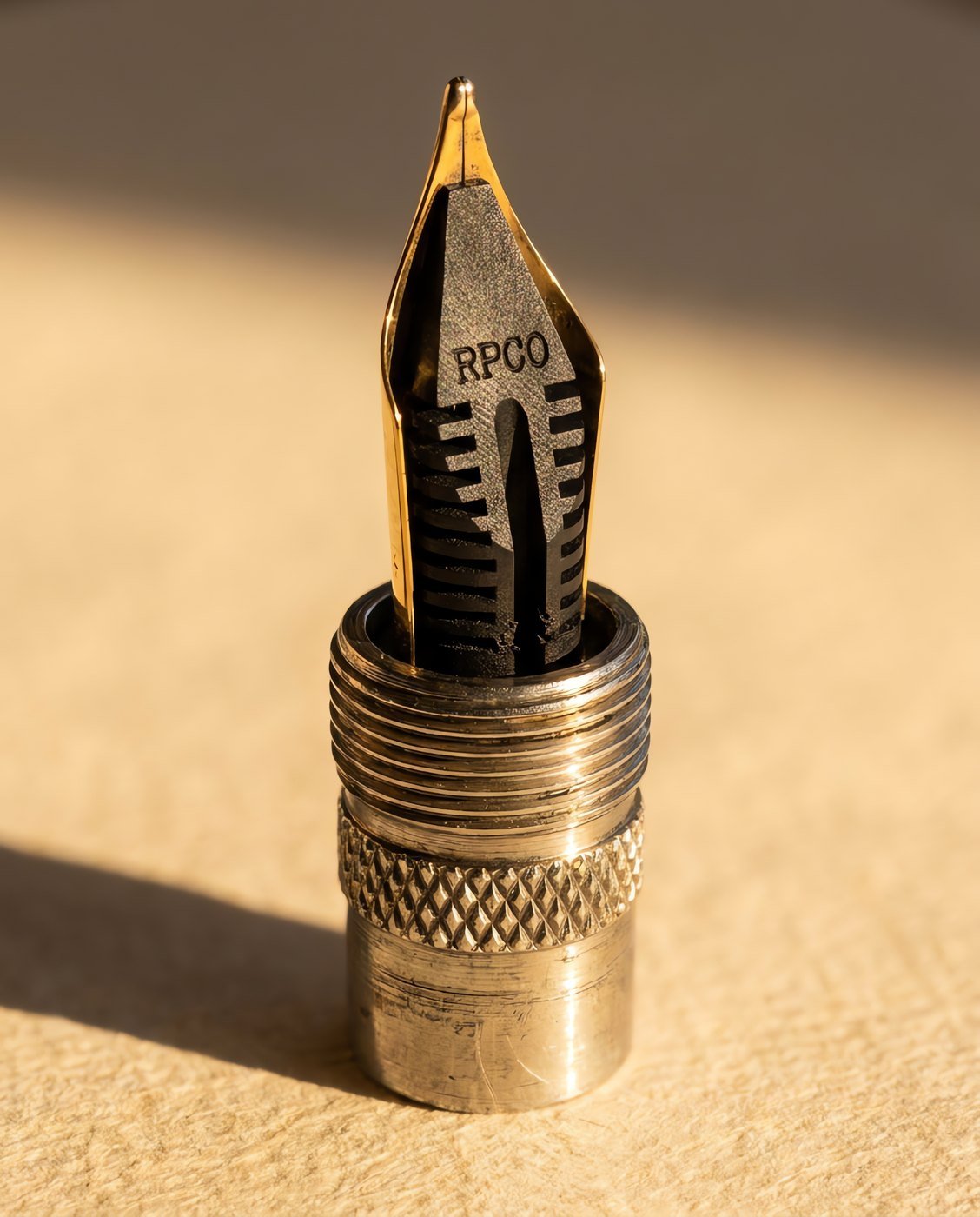 Nib Unit, No. 6 Gold-Plated — A screw-in fountain pen nib unit with a gold plated nib and black ebonite feed, standing upright, catching warm light in close detail.